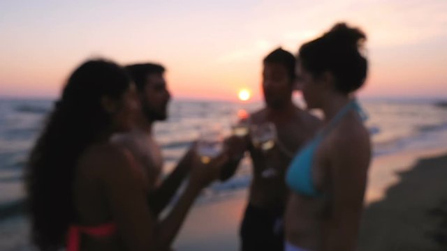 Young group of friends on the beach toasting at sunset- steady cam