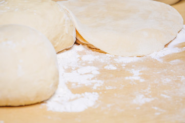 Rolled wheat dough and rolling pin on a wooden table