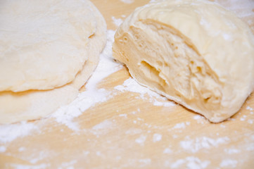 Rolled wheat dough and rolling pin on a wooden table