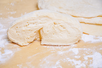 Rolled wheat dough and rolling pin on a wooden table