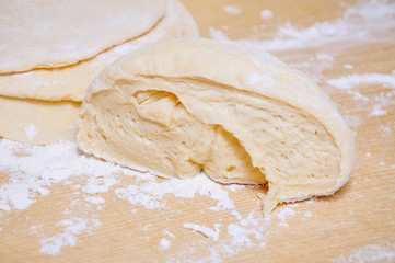 Raw wheat yeast dough rolled out into flat cakes on a table
