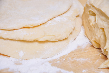 Rolled wheat dough and rolling pin on a wooden table