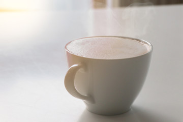 Cappuccino coffee white cup on white table with light effect in morning time background