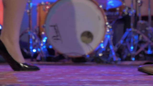 Male and female singers' dancing feet in front of drum kit