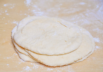 Raw wheat yeast dough rolled out into flat cakes on a table