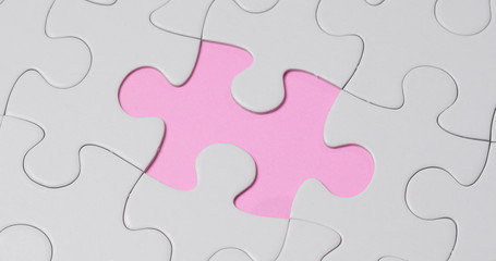 Completing white puzzle over pink background