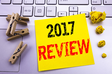Hand writing text caption inspiration showing 2017 Review. Business concept for Annual Summary Report written on sticky note paper on the white keyboard background.