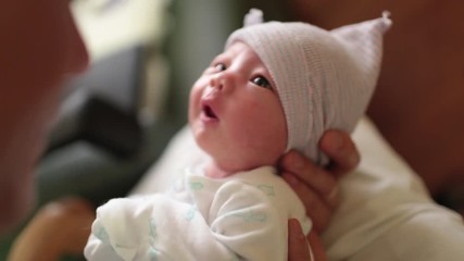 Father Kissing Newborn Baby in Hospital