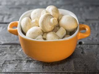 Fresh mushrooms in a yellow bowl on a rustic wooden table. Vegetarian food is on the table.