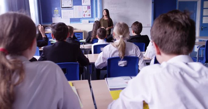 4K Young teacher talking to students in class, pupil putting hand up to answer a question. Slow motion