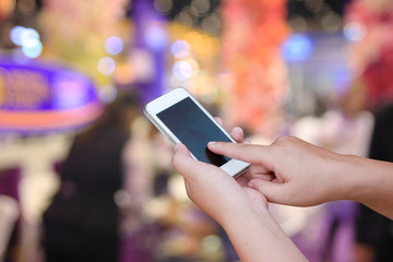 hand hold and touch screen smart phone, on abstract Businessmen and women blur in  work conference.