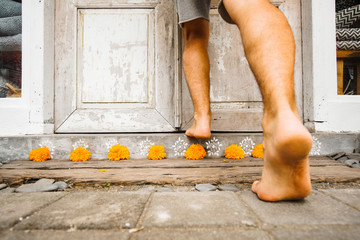 Male bare feet enter the house stepping over the threshold with flowers. The traditional entrance...
