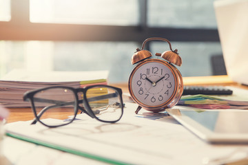 Business and finance concept of office working, Closeup clock and eyeglasses on office desk