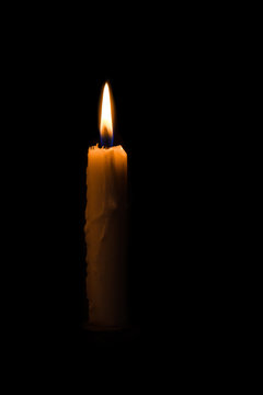One light candle burning brightly in the black background
