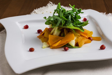 Fruit salad with apples and pomegranate on a square plate
