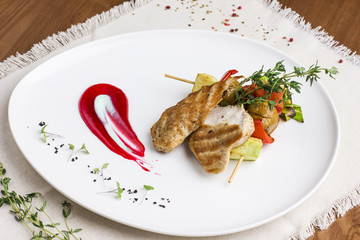 Chicken fillet with vegetables grilled on a skewer with sauce and greens