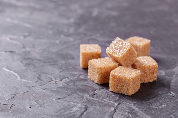 Brown cane sugar cubes pile on a black background. Copy space for text