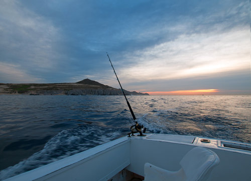Sunrise view of fishing rod on charter fishing boat on the Pacific side of Cabo San Lucas in Baja California MEX BCS