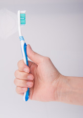 toothbrush in hand on background.