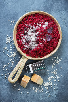 Risotto with beetroot served in a frying pan over blue stone background, top view, vertical shot