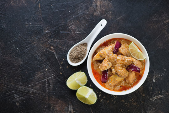 Massaman curry with chicken on a dark brown stone background, horizontal shot with copy space, view from above