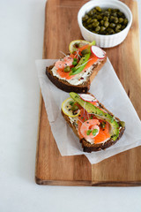 Smorrebrod, traditional Danish open sanwiches, dark rye bread with salmon, avocado, shrimp and micro-green.