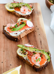 Smorrebrod, traditional Danish open sanwiches, dark rye bread with salmon, avocado, shrimp and micro-green.