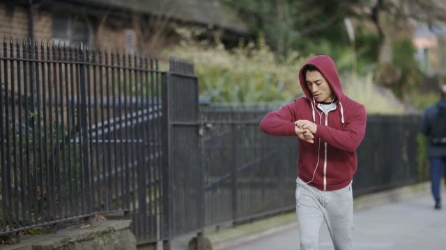 Young jogger checks his fitness tracker, in slow motion