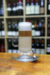 Cup of latte coffee on background of bottles.