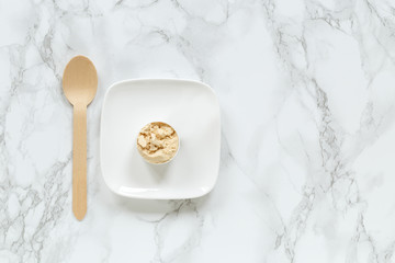 Protein powder in scoop on small plate against marble background