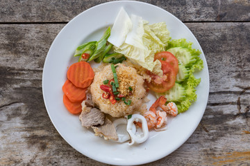 Fried rice with shrimp on the white dish on wooden table from top view