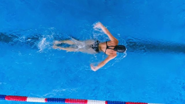 A female swimmer performs butterfly strokes with large splashes. 