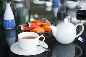 Cup of tea and tea pot with fresh fruit salad