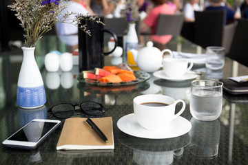 Cup of coffee and notebook with glasses pen with cell phone