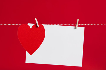 Red paper heart and blank white label pegged to a string