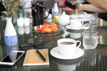 Cup of coffee and notebook with glasses pen with cell phone