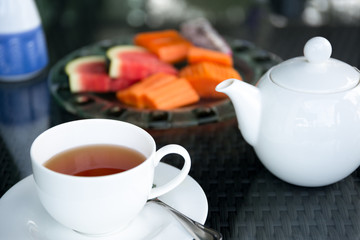 Cup of tea and tea pot with fresh fruit salad