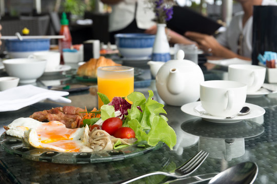 Breskfat set with fried eggs and vegetable salad with orange juice, tea pot and coffee