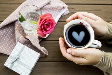 The heart is reflected in a cup of coffee, which is held by a woman's hands. Valentine's Day Concept