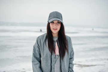 Stylish brunette girl in gray cap, casual street style on winter day.