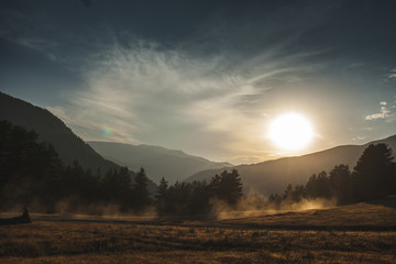 Amazing sunrise, mountains, trees and car dust