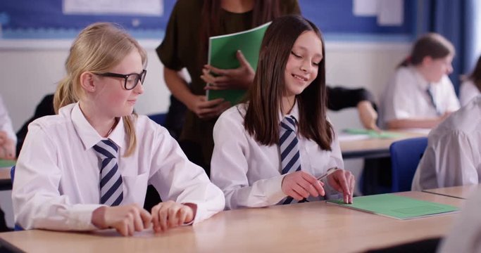 4k, Teacher handing out homework to school students in a classroom. Slow motion.