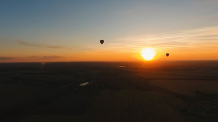 Aerial view Hot air balloon in the sky over a field in the countryside in the beautiful sky and sunset. Balloon silhouette with sunrise, Aerostat fly in the countryside.