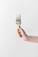 cropped image of woman holding brush in white paint isolated on white