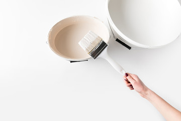 cropped image of girl holding brush in white paint on bucket isolated on white