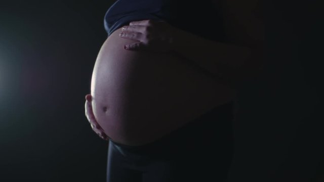 Side Profile Silhouette Lighting Close Up on Large Bare Belly of 9 Month Full Term Pregnant Mother