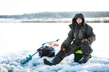 A young man is fishing from a hole on ice. Winter fishing