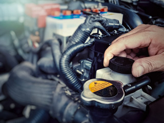 Obraz premium Close up hand of a mechanic man opening the Car radiator cap for checking water level in car engine