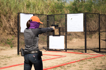 Woman aiming pistol in shooting range