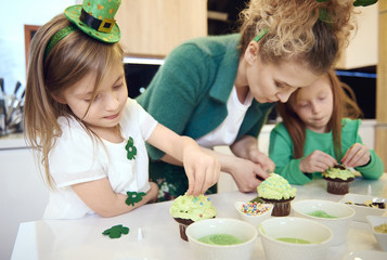 Family decorating cupcake at kitchen